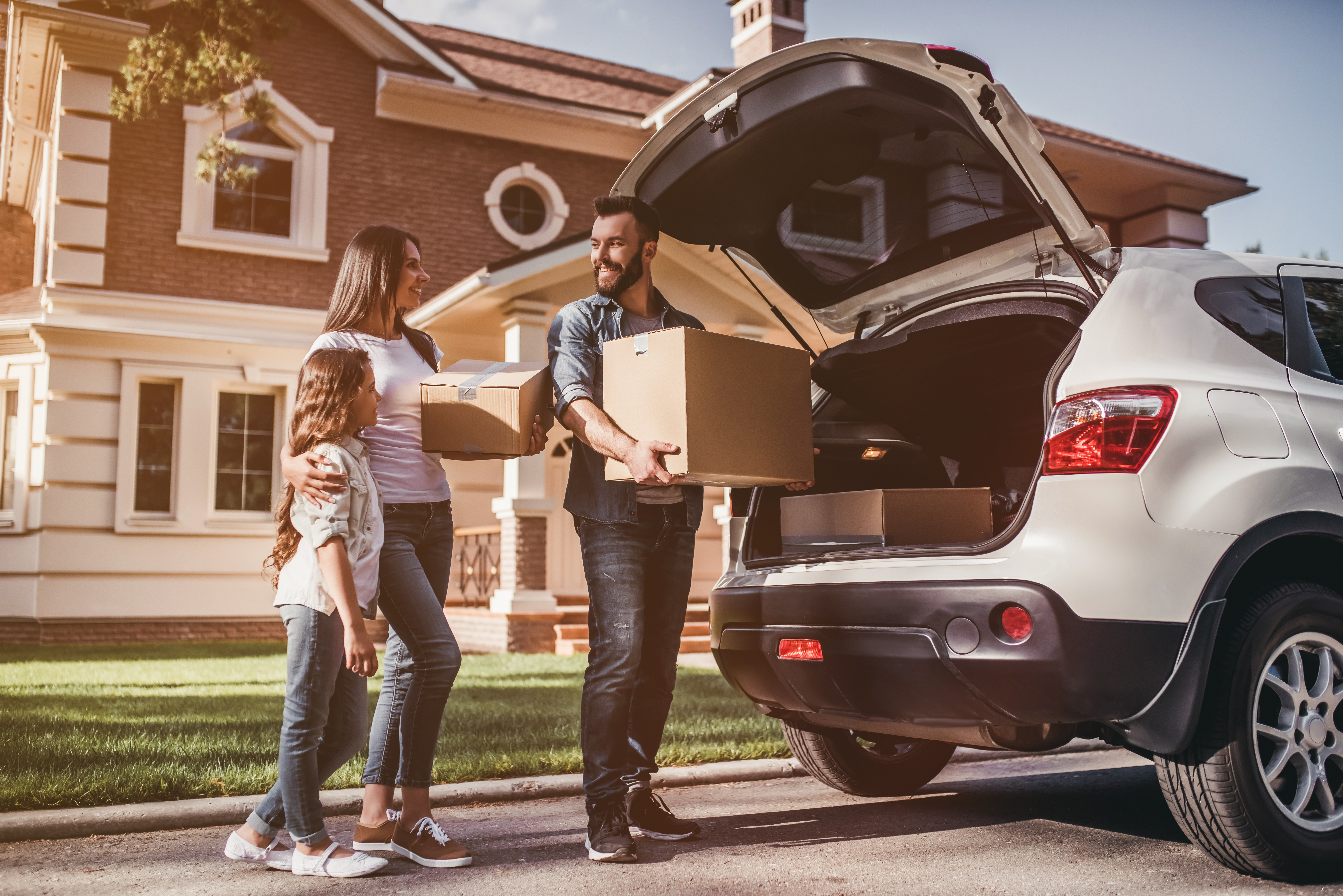 young family unloading moving boxes from truck