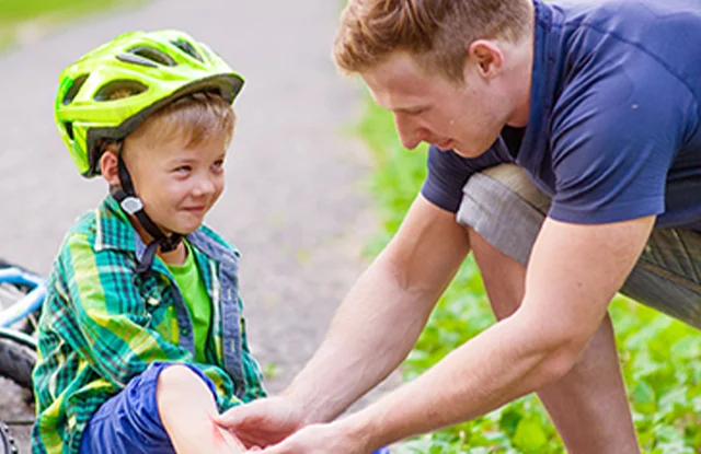 image of a father checking on his son after falling of his bike