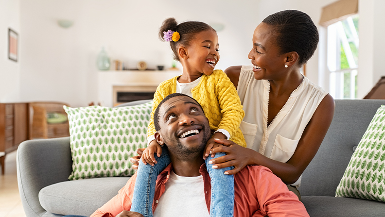 image of a mother, father and daughter sitting on the couch playing