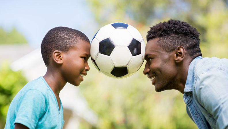 father and son playing soccer together