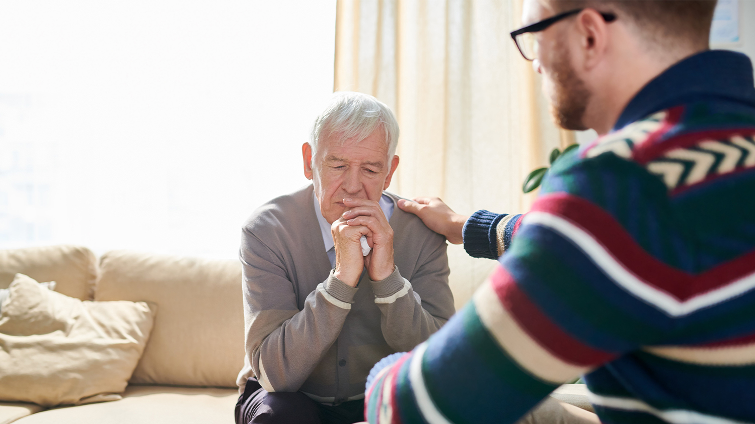 younger man comforting and elderly man